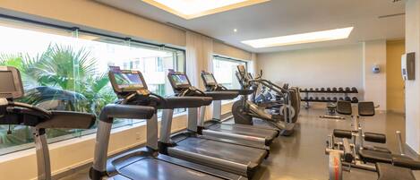 A gym with treadmills, weight machines, and dumbbells.