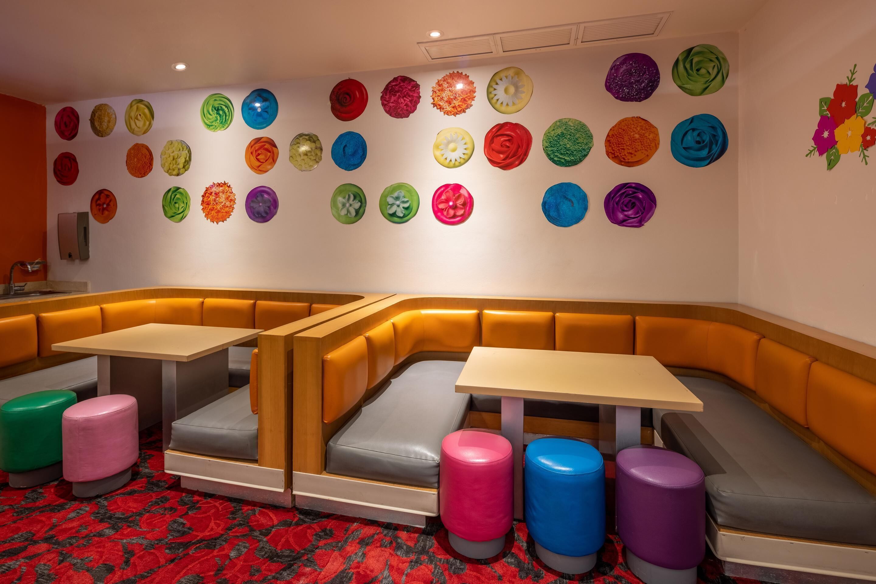 Um restaurante moderno com área de estar curvada, várias mesas e decorações coloridas nas paredes.