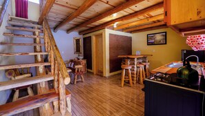 A rustic kitchen with wooden beams, a wooden staircase, and a brick wall. - Cabañas Las Gemelas Barrancas del Cobre (Urique)
