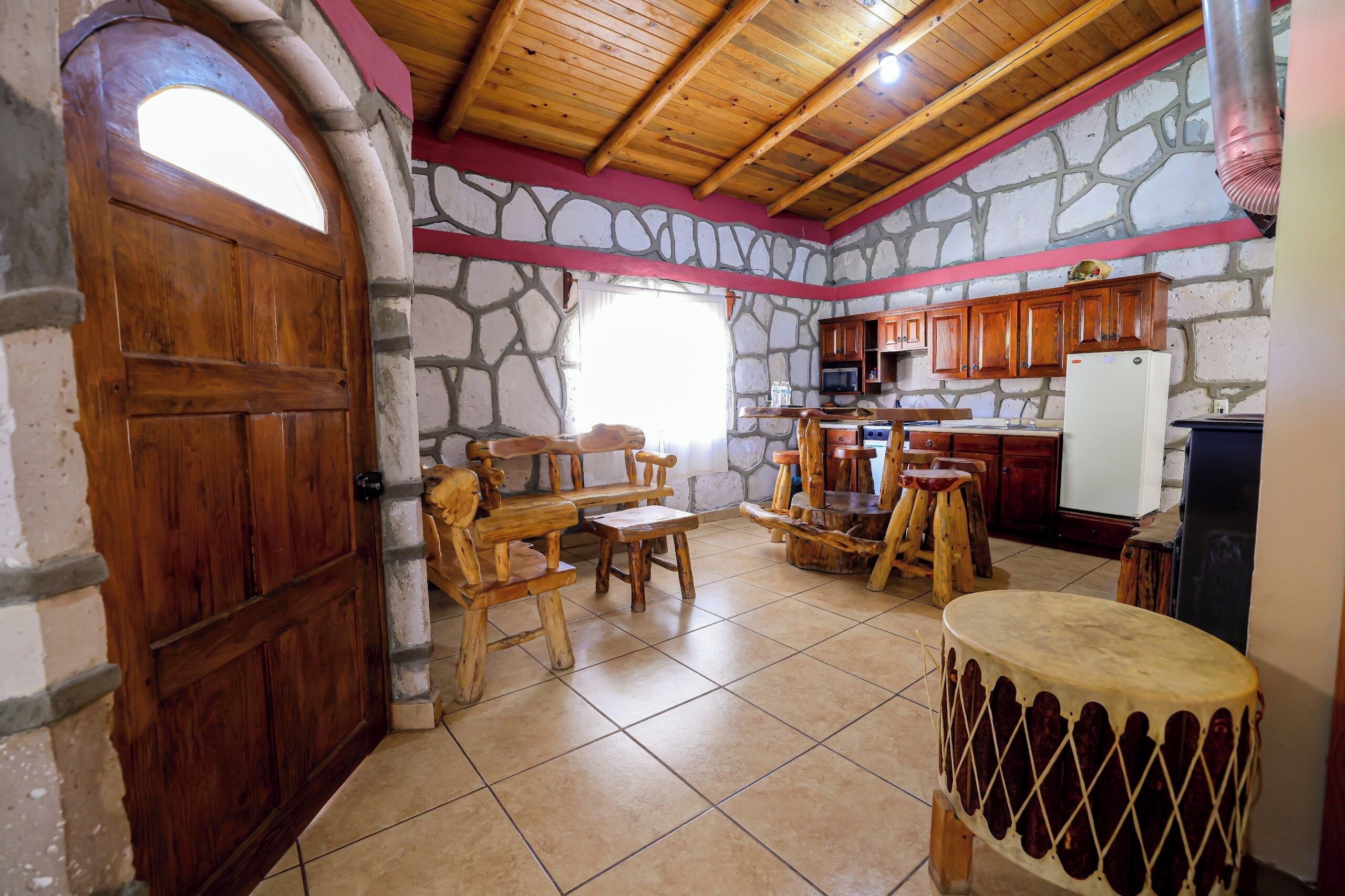 A rustic kitchen with stone walls, wooden furniture, and a large wooden door.