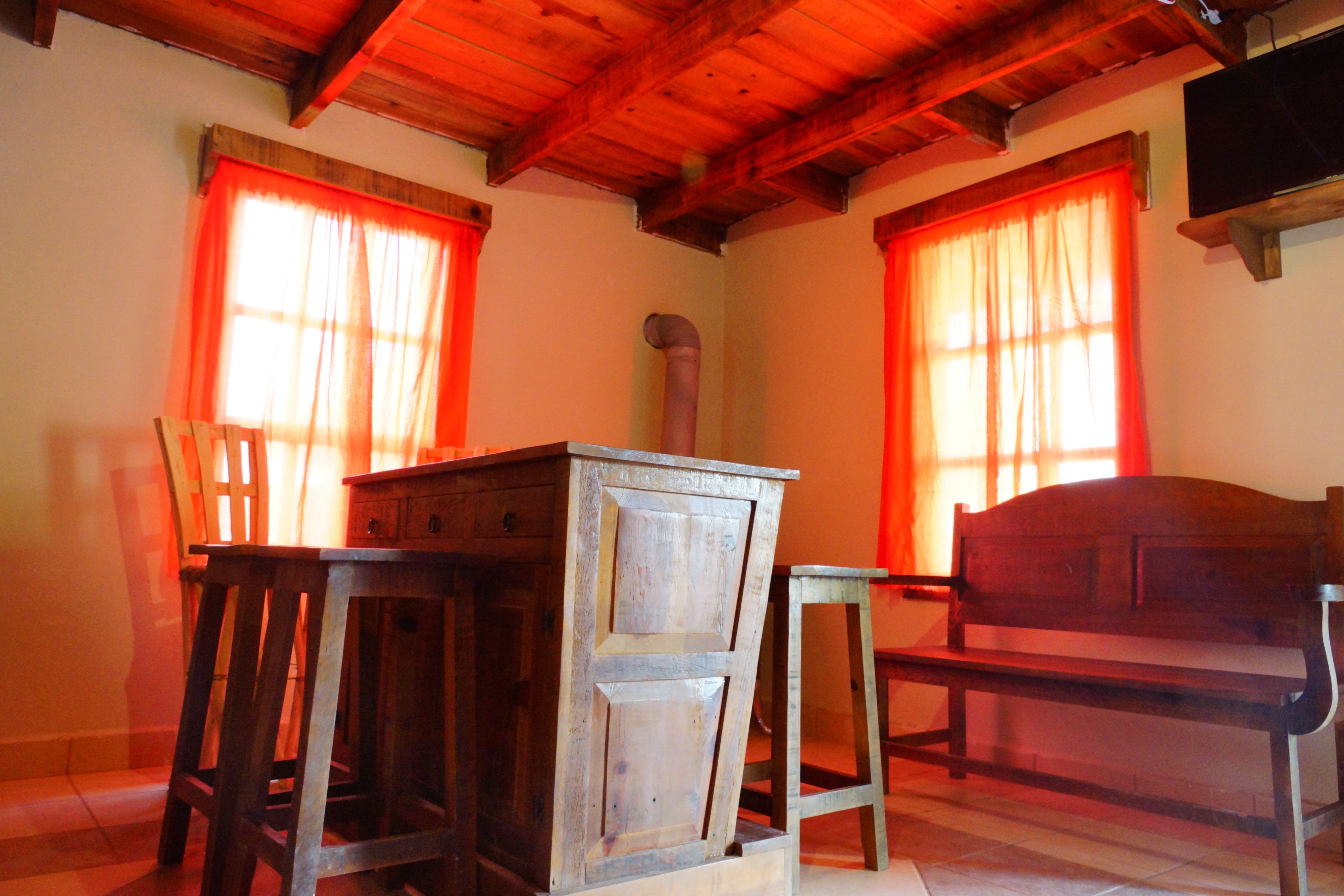 A room with a wooden table and bench, a chair, and a television on the wall.