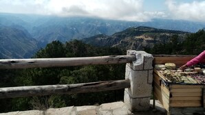 A wooden platform with a stone railing overlooking a mountainous landscape. - Cabañas Las Gemelas Barrancas del Cobre (Urique)