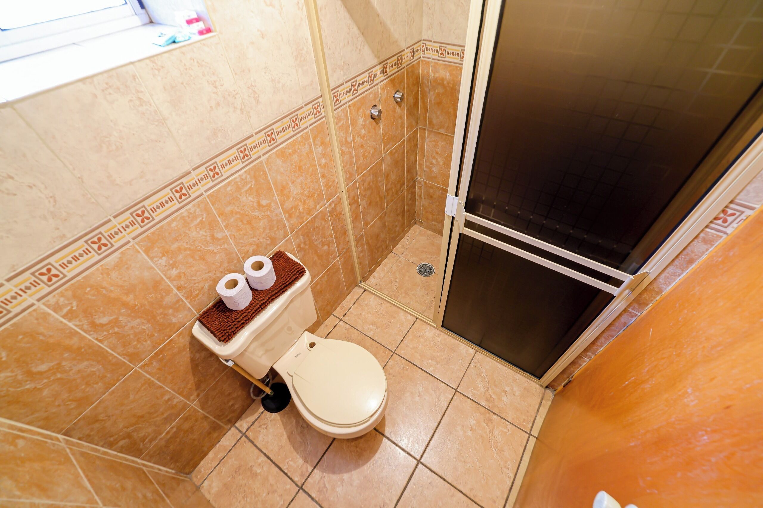 Une salle de bain avec des toilettes, une douche et des murs carrelés.