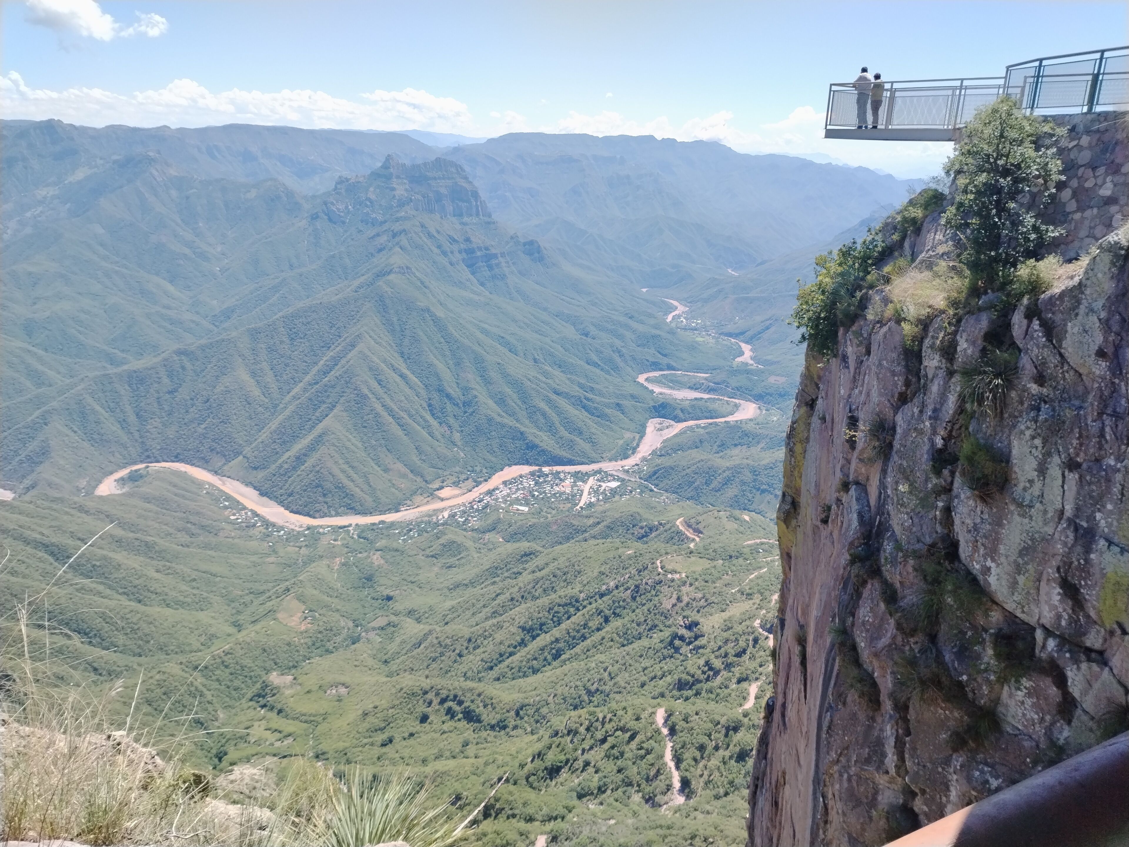 Paisaje montañoso con un río sinuoso y un acantilado rocoso.