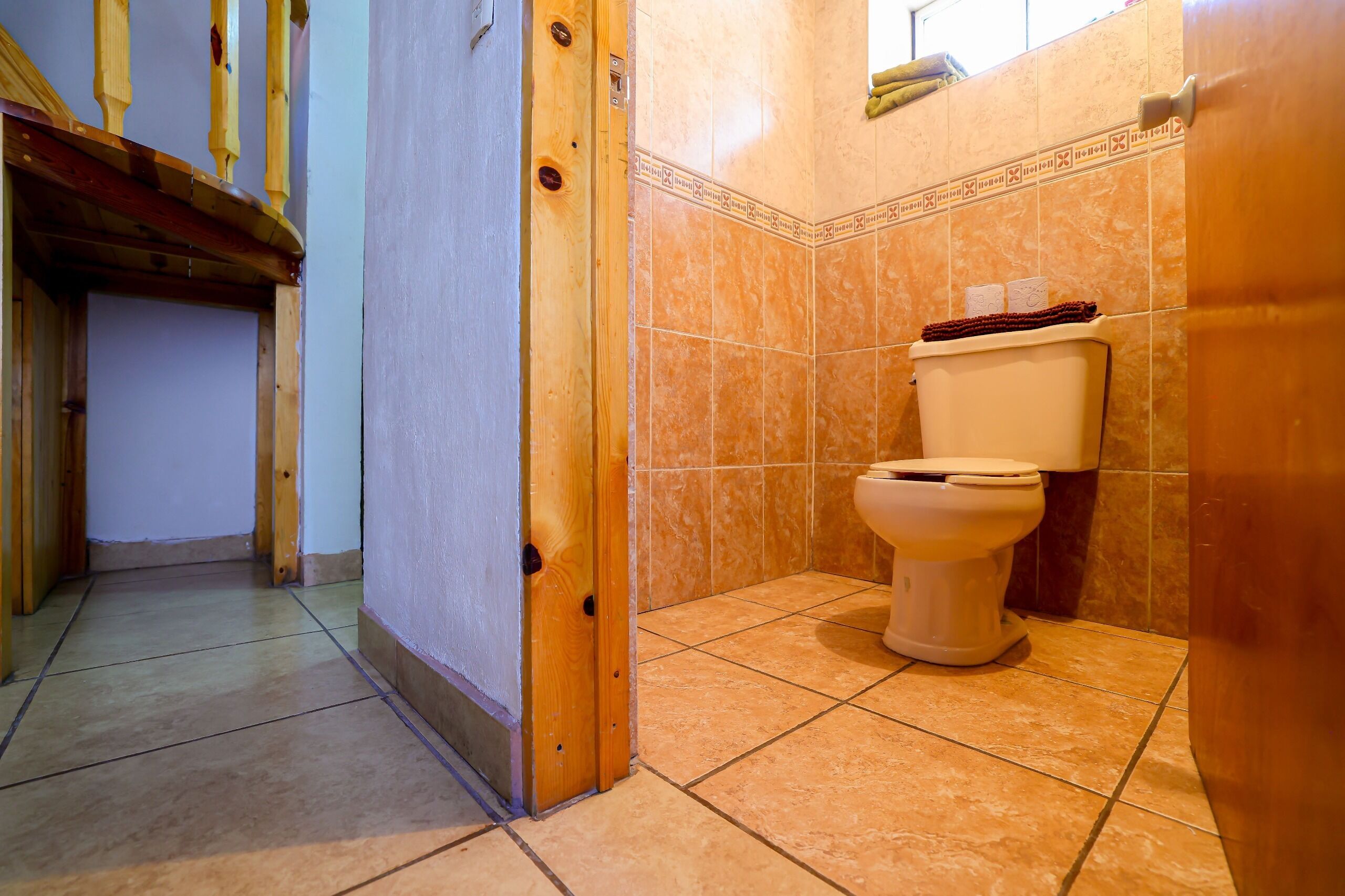 Une salle de bain avec des toilettes, des murs carrelés et un cadre de porte en bois.