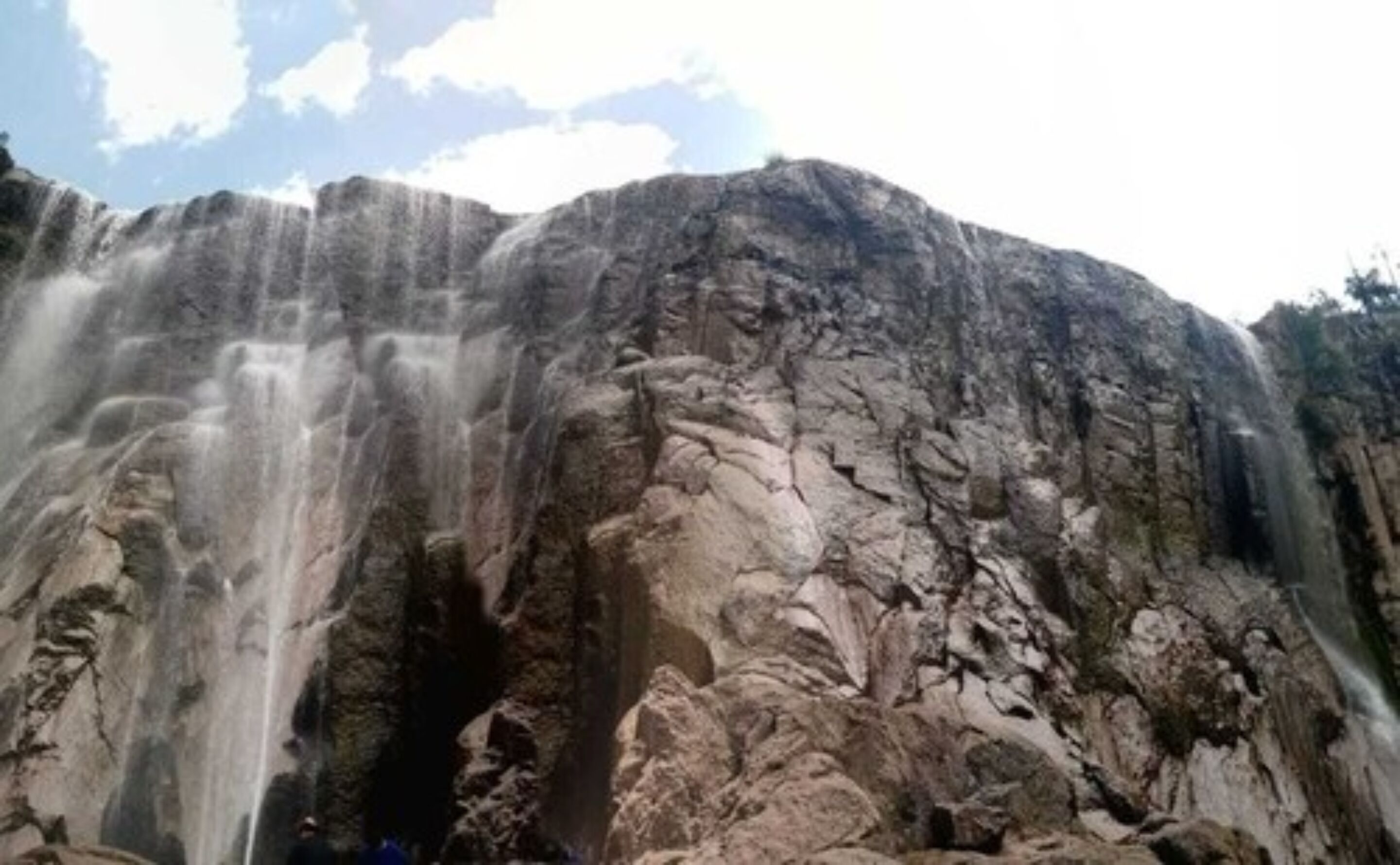 Una gran formación rocosa con una cascada deslizándose por su ladera.