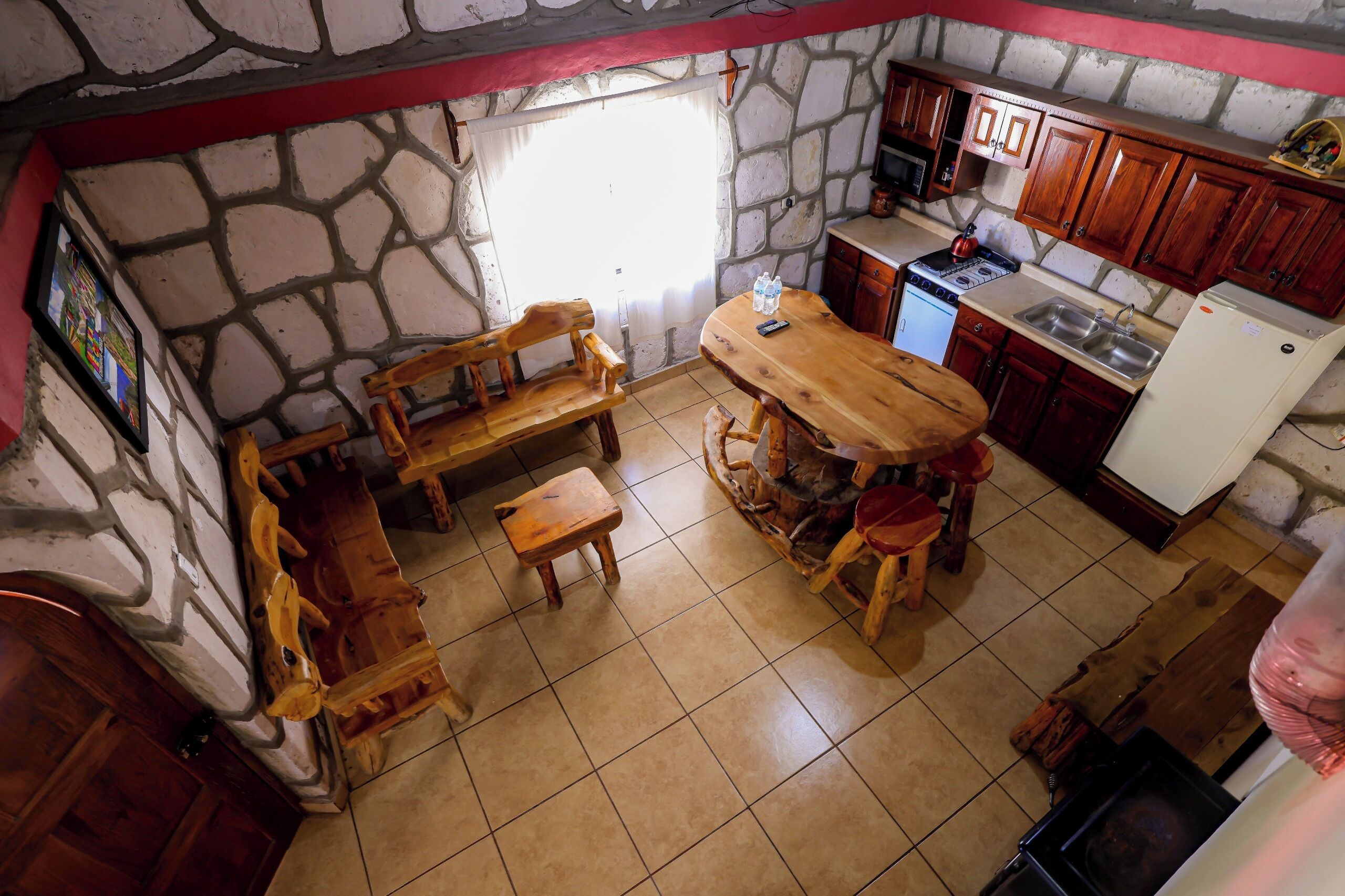 Une cuisine rustique avec des murs en pierre, des meubles en bois et des appareils  électroménagers simples.