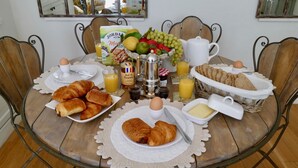 Una mesa de desayuno con croissants, huevos, pan y fruta.