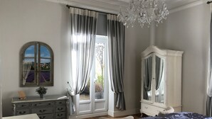 Un dormitorio con una cama grande, un aparador, un espejo y vistas a un campo de lavanda a través de una ventana.