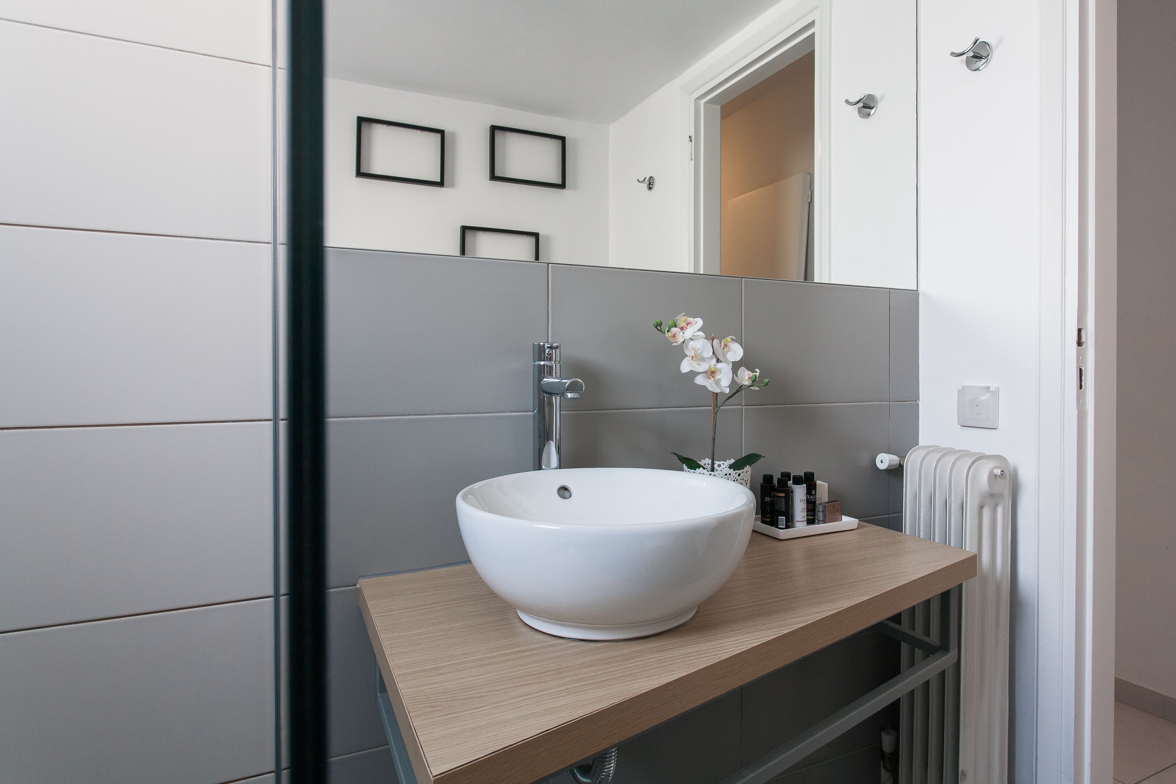 A modern bathroom with a large white sink, a mirror, and a towel rack.