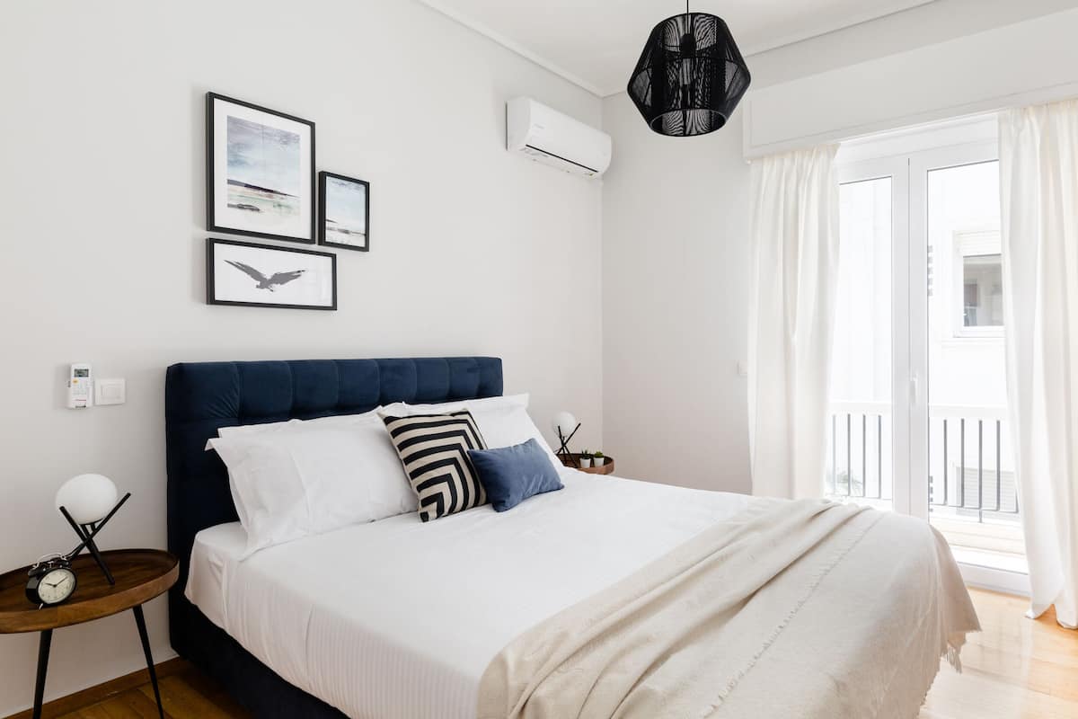 A modern bedroom with a large bed, a bedside table with a lamp, and artwork on the wall.