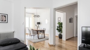 Un salon moderne avec un canapé, un téléviseur et un coin repas comprenant une table et des chaises.