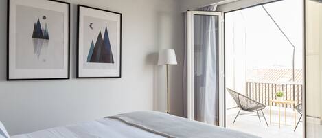 Quarto de hotel com uma cama, uma luminária e duas obras de arte emolduradas na parede.