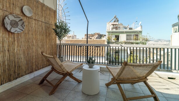 Un balcon avec deux fauteuils en osier, une petite table et un mur décoratif.