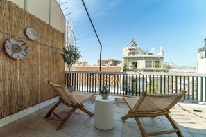 A balcony with two wicker chairs, a small table, and a decorative wall. - UPSTREET Central Cozy Apartments in Plaka (Athens)