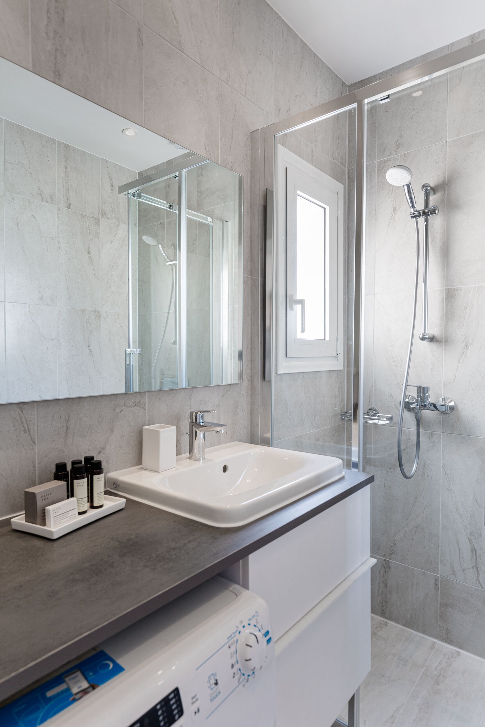A modern bathroom with a glass-enclosed shower, a white sink, and a large mirror.