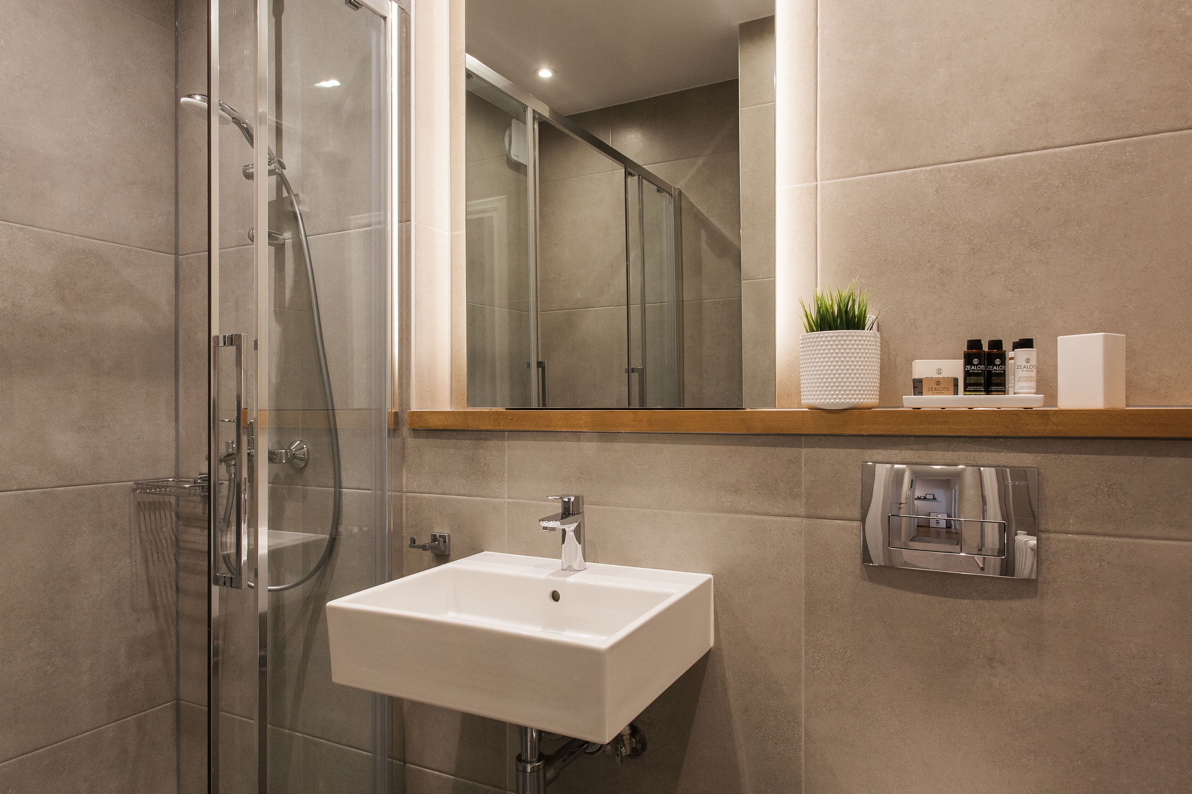 A modern bathroom with a glass-enclosed shower, a white sink, and a mirror above it.