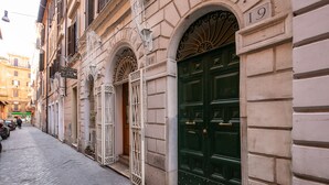 A narrow cobblestone street lined with historic buildings, featuring ornate metal gates and a prominent green door with a number plaque. - Maison Babuino with a panoramic terrace (Roma)