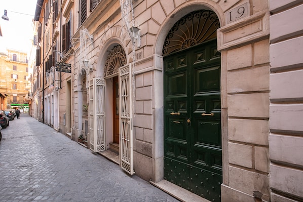 A narrow cobblestone street lined with historic buildings, featuring ornate metal gates and a prominent green door with a number plaque. - Maison Babuino with a panoramic terrace (Roma)