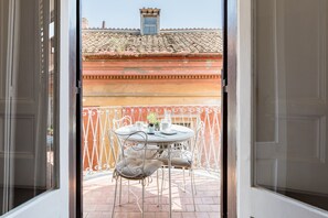 An open balcony with a table and chairs, a view of a building with a tiled roof, and a metal railing. - Maison Babuino with a panoramic terrace (Roma)