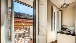 A kitchen with a sink, a small table, and a chair outside a door. - Maison Babuino with a panoramic terrace (Roma)