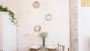 Una mesa de comedor dispuesta con platos, vasos y cubiertos, rodeada de sillas.