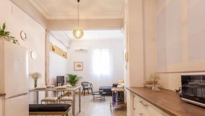 Una cocina compacta con piso estampado, una zona de comedor con banco y un televisor en la encimera.