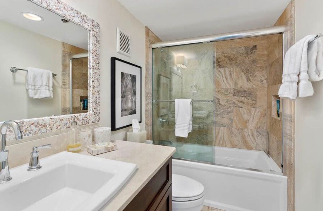 A bathroom with a double sink, a large mirror, a shower enclosure, and a toilet.