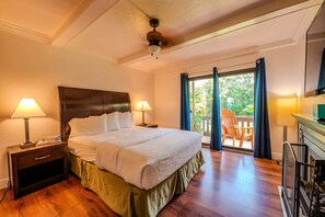 A hotel room with a large bed, two bedside tables with lamps, a ceiling fan, and a view of the outdoors through a sliding glass door. - Toucans Retreat  (South Padre Island)