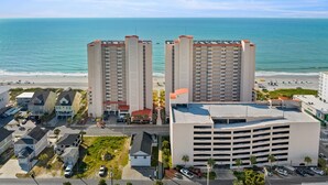 Un hotel costero con dos edificios altos, un estacionamiento y vistas a la playa.
