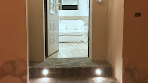 Een trap die leidt naar een kamer met een witte bank en een flatscreen televisie.