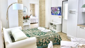 Een moderne slaapkamer met een bed, nachtkastje, dressoir en een televisie.