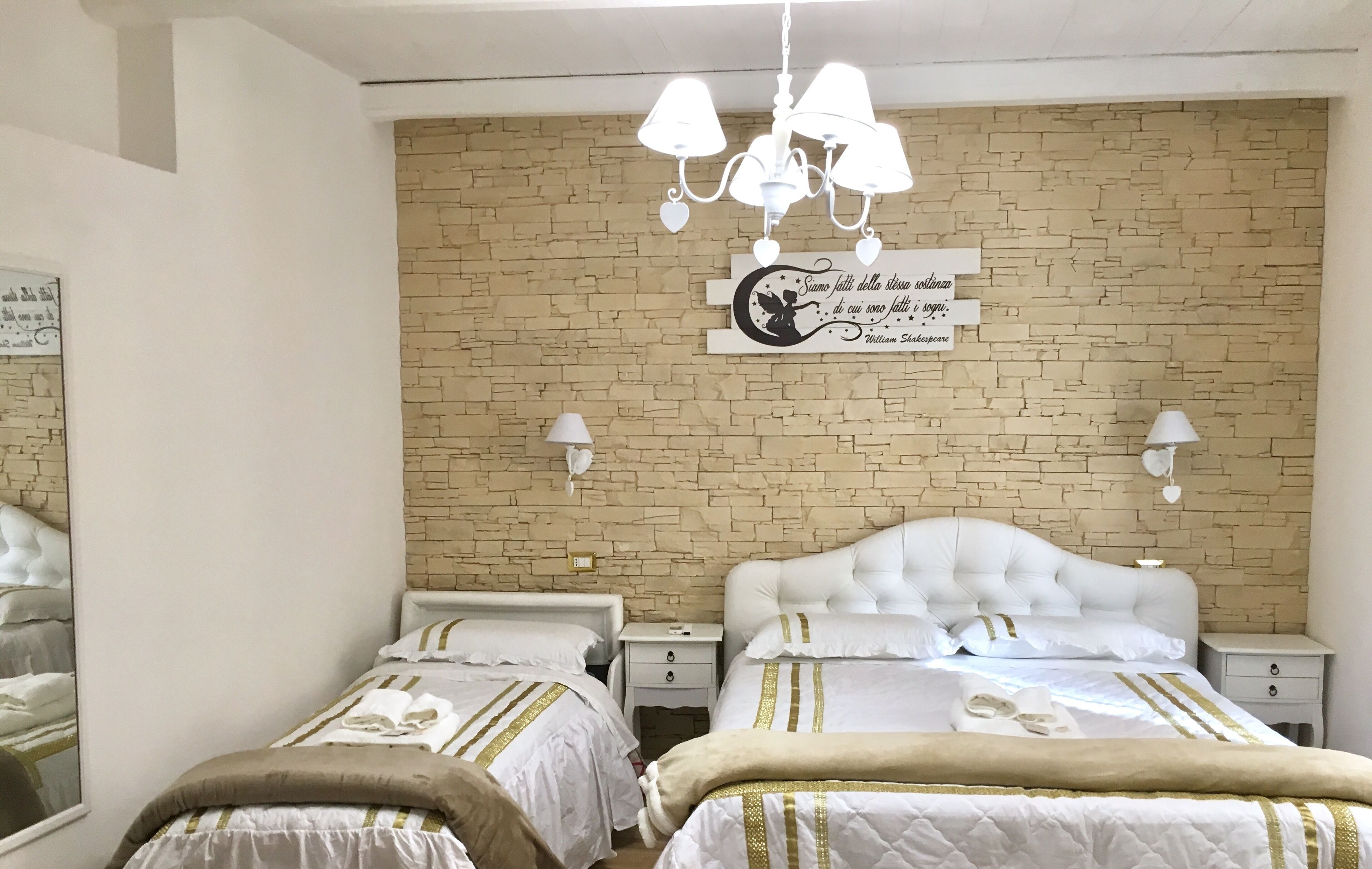 Une chambre d’hôtel avec deux lits, un mur décoré d’un motif en briques, un lustre et une enseigne décorative.