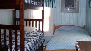 A room with a bunk bed, a single bed, and a small table.