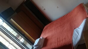 Una habitación con una cama, una ventana con persianas, un armario y un aire acondicionado de pared.