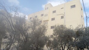 A multi-story building with a flat facade, several windows, and a visible antenna on the roof.