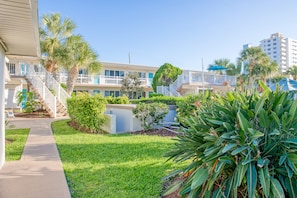 Stroll through the beautifully landscaped courtyard, surrounded by lush greenery and modern buildings with balconies.