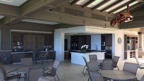 Ein Patio im Freien mit runden Tischen und Stühlen, einer Barbereich in der Mitte sowie einer großen, hängenden Skulptur.