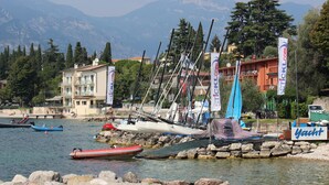 Un port de plaisance avec des bateaux amarrés, une enseigne indiquant la possibilité de louer des yachts, et un bâtiment doté d’un balcon donnant sur l’eau.