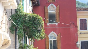 Un bâtiment rouge avec des fenêtres en arc de cercle et un balcon orné de plantes.