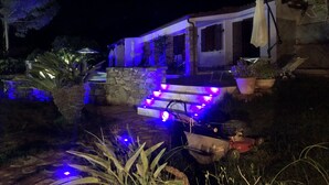 Une maison avec des marches en pierre menant à un porche, éclairé par des lumières bleues.