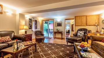 A spacious living room with leather sofas, a coffee table with a fruit bowl, and a patterned rug.