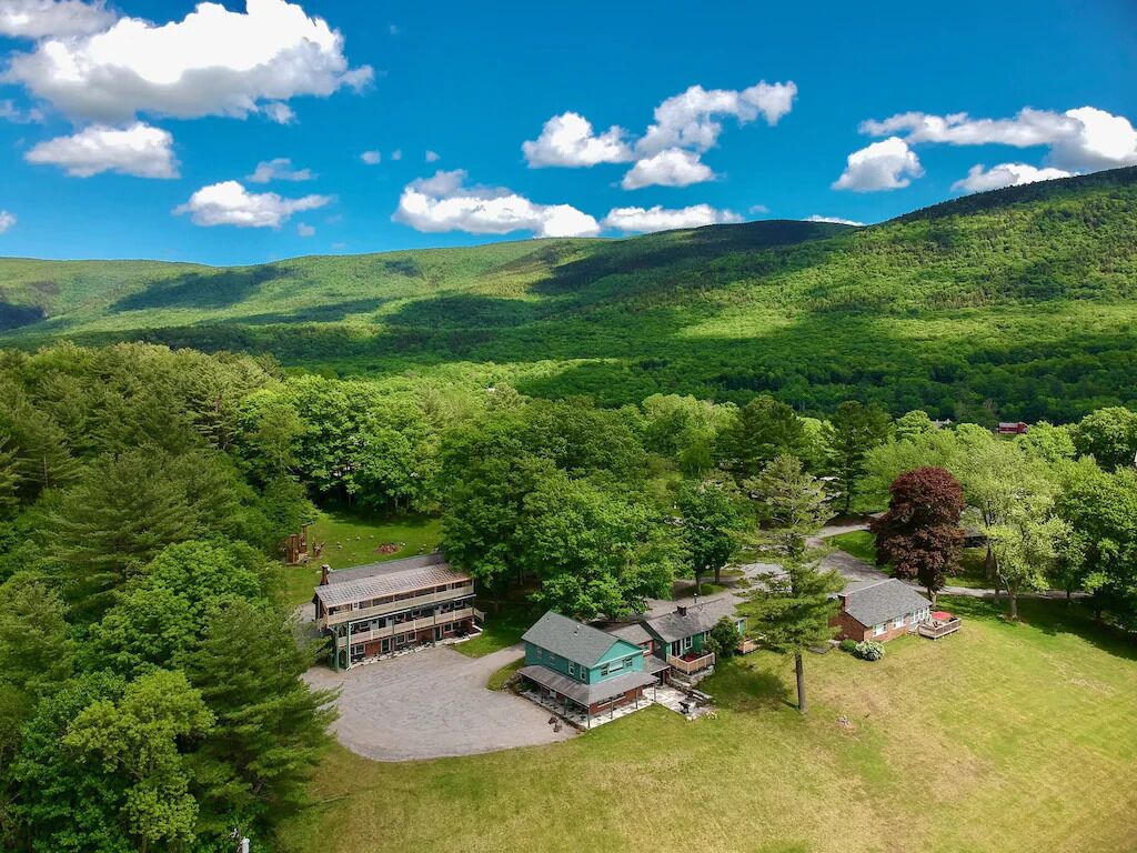An aerial view of a property with a large house, a guesthouse, and a driveway.