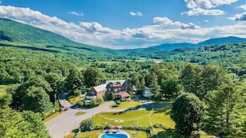 An aerial view of a large estate with a swimming pool, tennis court, and a spacious lawn.