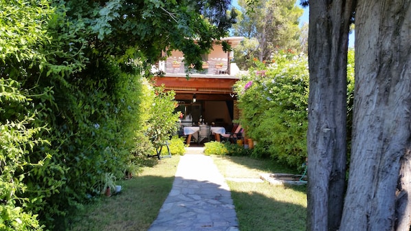 A garden pathway leading to a covered outdoor dining area with tables and chairs.