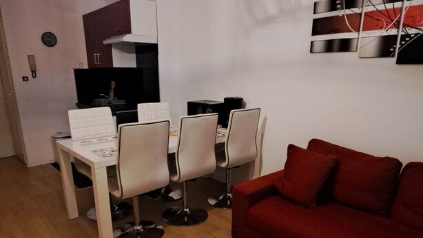 A compact living space with a dining area, a red sofa, and a white table.