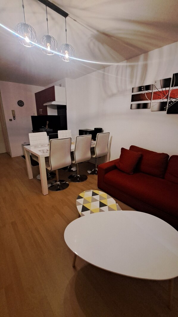 A compact living space with a dining area, a red sofa, and a white table.