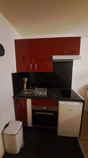 Uma cozinha compacta com geladeira, forno e micro-ondas.