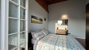 A bedroom with a large bed, a dresser, a mirror, and a window with blinds. - Holidays Lake Garda Sirmione Peschiera and Desenzano del Garda (Pozzolengo)