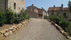 Um caminho de cascalho estreito, ladeado por muros de pedra e edifícios tradicionais de pedra com telhados inclinados.